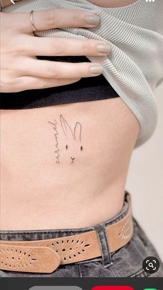 a woman's stomach with a small bunny tattoo on the side, and an image of a rabbit behind her belly