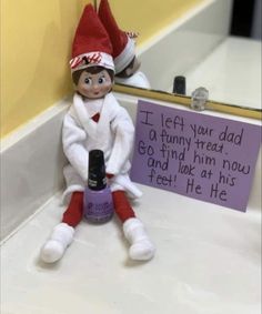 an elf is sitting on the counter next to a sign