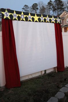 a white curtain with yellow stars hanging from it's sides in front of a house