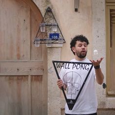 a man holding up a sign that says wall pong in front of his face