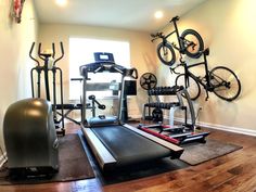 an exercise room with stationary bikes and treadmills on the wall next to a window