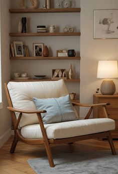 a white chair sitting in front of a window next to a wooden shelf filled with books