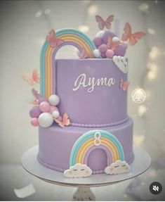 there is a purple cake with rainbows and clouds on it