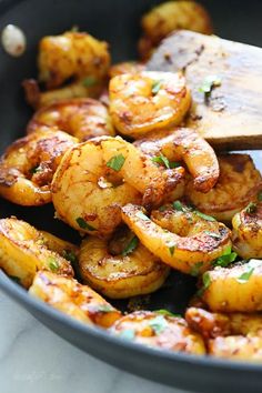 shrimp being cooked in a skillet with a wooden spoon