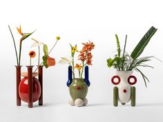 three vases with flowers and plants in them