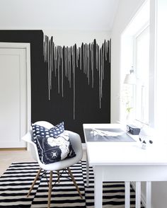 a black and white living room with dripping paint on the wall, striped rug, and chair