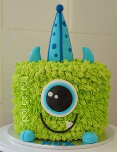 a green cake with blue decorations and a monster face on the top is sitting on a table