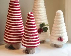 three knitted christmas trees sitting on top of a white table next to each other