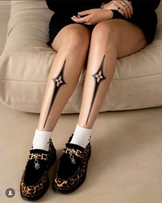 a woman sitting on top of a couch with her legs crossed and tattoos on them