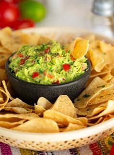 a bowl filled with guacamole and tortilla chips on top of a table