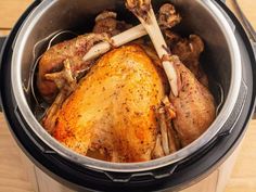 a close up of a chicken in an electric pressure cooker on a wooden table