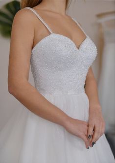 a woman in a white wedding dress holding onto her ring