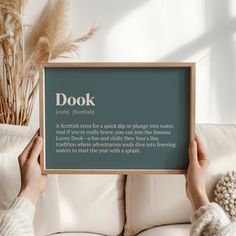 a person holding up a sign with the words dook on it in front of a white couch