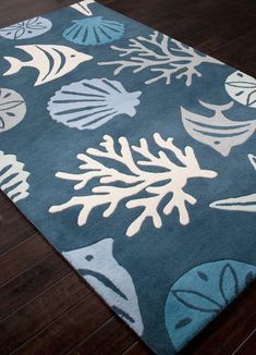 a blue rug with white corals and seashells is on the wooden floor