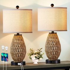 two lamps sitting on top of a table next to a vase with flowers in it