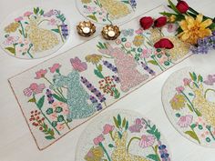 four place mats with flowers on them and candles next to each other in the middle