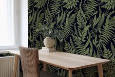 a table and chair in front of a wall with green leaves on it