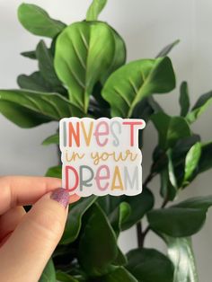 someone holding up a sticker that says invest in your dream