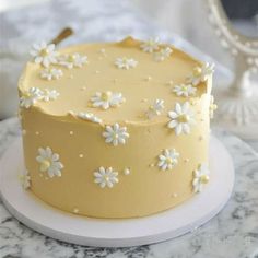 there is a yellow cake with white flowers on the top and bottom, sitting on a marble table