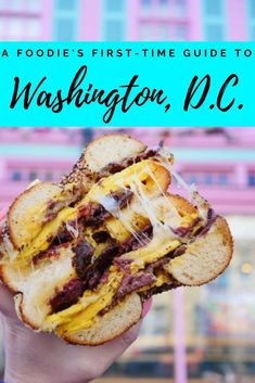 a person holding up a sandwich in front of a pink building with the words washington, d c on it