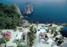 people are lounging on lounge chairs near the water and cliffs in caprifi, italy