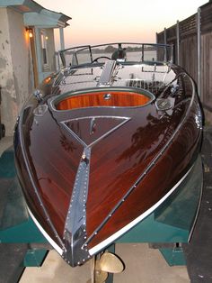 a brown and white boat sitting on top of a wooden floor next to a building