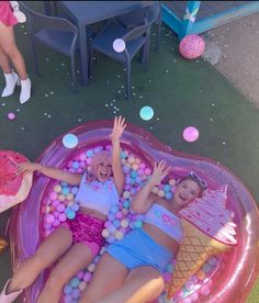 two girls in an inflatable pool with ice cream cones and balls on it