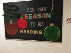 a sign that says tis the season to be reading with ornaments hanging from it's sides