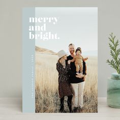 a merry and bright holiday card with an image of two people holding a baby in their arms