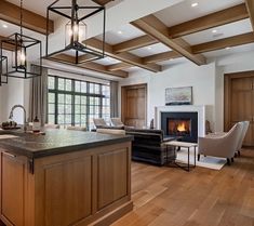 a large open concept living room and kitchen area with wood flooring, exposed beams, an island in the center