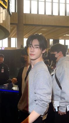 two young men standing next to each other in front of a crowd at an airport