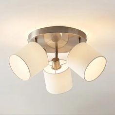 three white lamps are on the ceiling in this modern style light fixture with four shades