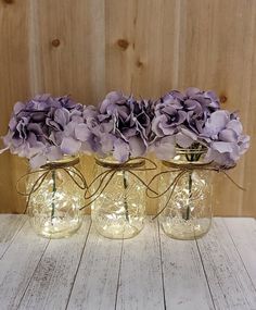 three glass vases with purple flowers in them