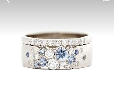 two wedding bands with blue and white diamonds on them, one has a center diamond in the middle