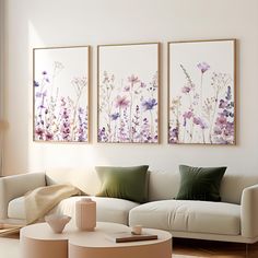 three paintings hang on the wall above a white couch and coffee table in a living room