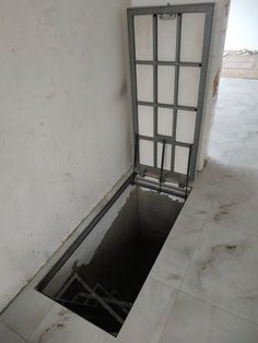 a drain in the ground with bars on it's sides and an open door