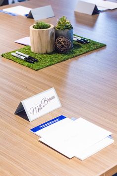 a wooden table topped with lots of cards and envelopes next to a potted plant