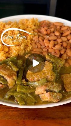 a white plate topped with beans, rice and green beans next to other food on a wooden table