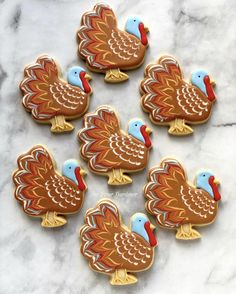 six decorated turkey cookies sitting on top of a marble counter