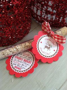 some red and white paper tags are next to a wine cork with a ribbon on it