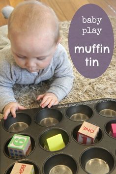 a baby playing with wooden blocks in a muffin tin