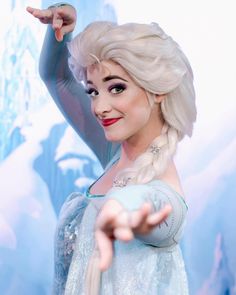 there is a woman dressed as frozen queen pointing to something on the wall behind her