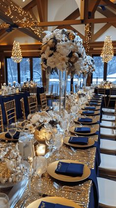 a long table set with blue and white place settings, gold chargers and silver napkins