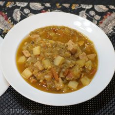 a white bowl filled with soup sitting on top of a black and white table cloth