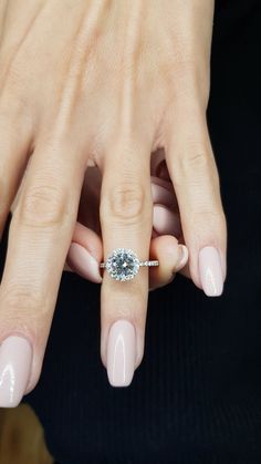 a woman's hand with a diamond ring on her finger and pink manicures