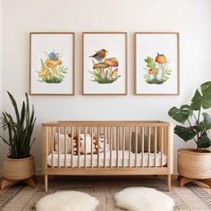 a baby crib with three pictures on the wall above it and two potted plants