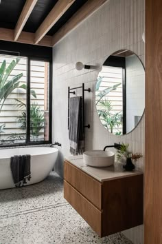 a bath room with a tub a sink and a mirror on the wall next to a window