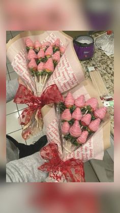 a bunch of strawberries wrapped in paper and tied with red ribbon on top of a counter