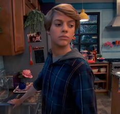 a young boy standing in the middle of a kitchen