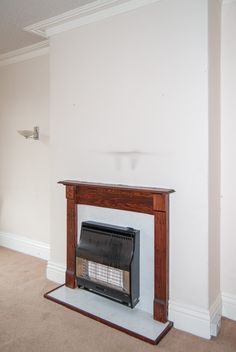 an empty room with a fire place in the middle and carpet on the floor below